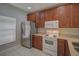 Well-lit kitchen featuring stainless steel refrigerator, white range and microwave, and wooden cabinets at 8531 Trail Wind Dr, Tampa, FL 33647