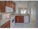 Bright kitchen with white appliances, brown cabinets, and a tiled floor at 8531 Trail Wind Dr, Tampa, FL 33647