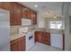 Kitchen showcasing white appliances, wooden cabinets, and a view to another room at 8531 Trail Wind Dr, Tampa, FL 33647