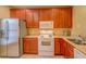 Kitchen featuring stainless steel refrigerator, white microwave, wood cabinets and tile floor at 8531 Trail Wind Dr, Tampa, FL 33647