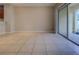 Open-concept living room with neutral walls, tile flooring, and sliding glass doors to outdoor space at 8531 Trail Wind Dr, Tampa, FL 33647