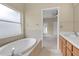 Bright bathroom features a soaking tub, tiled floor, and a doorway leading to another room at 9644 Jasmine Brook Cir, Land O Lakes, FL 34638