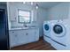 Well-lit laundry room featuring modern washer and dryer, sink, and white cabinets at 9706 N 22Nd St, Tampa, FL 33612