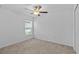 Neutral bedroom with a ceiling fan, closet, and a large window overlooking the landscaped lawn at 10433 Alder Green Dr, Riverview, FL 33578