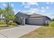 Single-story home with a two car garage, manicured landscaping, and beautiful palm trees at 10433 Alder Green Dr, Riverview, FL 33578