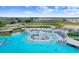 Aerial view of a community pool with sandy beach, aqua park, and plenty of seating at 10998 Gable Dig Loop, San Antonio, FL 33576