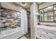 Bathroom with tub, shower, gray tiles, white vanity, and mirror at 1111 32Nd N St, St Petersburg, FL 33713
