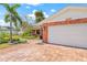 Spacious two-car garage attached to a brick home with a paver driveway and lush landscaping at 1141 80Th Street S Ct, St Petersburg, FL 33707