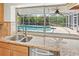 Modern kitchen featuring granite countertops, stainless steel appliances, and a view of the screened-in pool and landscaped yard at 1141 80Th Street S Ct, St Petersburg, FL 33707