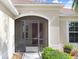 Close-up of the home's screened front entry, showcasing a red front door, neutral siding, and manicured landscaping at 13411 Graham Yarden Dr, Riverview, FL 33579