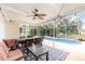 A screened-in patio with tables, chairs, fan, and view of pool offers space to relax and entertain at 1350 Mustang St, Nokomis, FL 34275