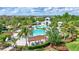 Aerial view of a community pool, featuring cabanas and a splash pad, surrounded by palm trees at 13518 Circa Crossing Dr, Lithia, FL 33547