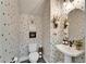 Stylish powder room with modern fixtures, decorative mirror, pedestal sink, and spotted wallpaper at 14204 Barrington Stowers Dr, Lithia, FL 33547