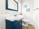 Charming bathroom with a navy blue vanity, a white sink, and wainscoting on the lower half of the walls at 14330 Oliver St, Largo, FL 33774