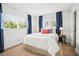 Bright bedroom with two windows dressed with blue curtains, a plush bed with a white quilt and decorative pillows at 14330 Oliver St, Largo, FL 33774
