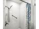 Clean white tiled shower with a shower head, grab bar, and a patterned shower curtain for accessibility at 14330 Oliver St, Largo, FL 33774
