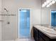 Bathroom featuring double sinks, dark vanity, tiled floor, and a shower behind frameless glass at 15579 Stone House Dr, Brooksville, FL 34604