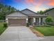 Charming home with a two-car garage, covered porch, and manicured lawn at 15579 Stone House Dr, Brooksville, FL 34604