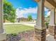 Inviting front porch with stone pillars and a green tree in the yard with a blue sky background at 15579 Stone House Dr, Brooksville, FL 34604