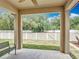 View of the backyard from covered patio with bench, ceiling fan and concrete flooring at 15579 Stone House Dr, Brooksville, FL 34604