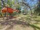 Large backyard featuring a covered picnic area, mature trees, and plenty of space for outdoor activities at 16224 Iola Woods Trl, Dade City, FL 33523