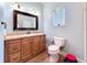 Well-lit bathroom featuring wood vanity with cultured marble top, framed mirror, and decorative fixtures at 16224 Iola Woods Trl, Dade City, FL 33523