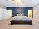 This primary bedroom features a dark blue accent wall, carpeted floors, and a decorative ceiling fan at 16224 Iola Woods Trl, Dade City, FL 33523