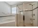 Bright bathroom featuring a corner tub and glass-enclosed shower with black tile accents at 2218 Valterra Vista Way, Valrico, FL 33594