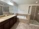 Bathroom featuring double sink vanity, bathtub, and glass shower at 2731 Hampton Green Ln, Brandon, FL 33511