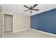 Bright bedroom features plush carpet, blue accent wall, and a modern ceiling fan at 28516 Tranquil Lake Cir, Wesley Chapel, FL 33543
