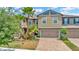 Inviting two-story townhouse with a brick-paved driveway, attached garage, and lush landscaping at 28516 Tranquil Lake Cir, Wesley Chapel, FL 33543