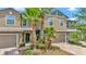 Inviting two-story townhouse with a brick-paved walkway, attached garage, and lush landscaping with palm trees at 28516 Tranquil Lake Cir, Wesley Chapel, FL 33543