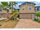 Inviting two-story townhouse with a brick-paved driveway, attached garage, and lush landscaping with palm trees at 28516 Tranquil Lake Cir, Wesley Chapel, FL 33543