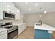 Modern kitchen with stainless steel appliances, quartz countertops, and a blue accent on the center island at 28516 Tranquil Lake Cir, Wesley Chapel, FL 33543