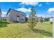 Manicured backyard with lush lawn, young tree, and screened patio at 3113 Marine Grass Dr, Wimauma, FL 33598