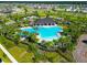 Aerial view of a community pool featuring a covered pavilion, lounge chairs, and lush landscaping at 3113 Marine Grass Dr, Wimauma, FL 33598