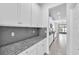 Bright kitchen featuring granite countertops, gray backsplash, and white cabinets at 3113 Marine Grass Dr, Wimauma, FL 33598