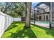 Artificial turf backyard with a screened in pool with a hot tub and covered patio with ceiling fans and an outdoor TV at 3117 W Knights Ave, Tampa, FL 33611