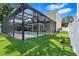 Artificial turf backyard with a screened in pool with a hot tub and covered patio with ceiling fans and an outdoor TV at 3117 W Knights Ave, Tampa, FL 33611