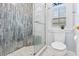 Bathroom featuring a glass shower with unique gray tiling and a windowed toilet area at 3117 W Knights Ave, Tampa, FL 33611