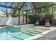 Screened in pool with chairs and steps leading in, as well as an attached hot tub at 3117 W Knights Ave, Tampa, FL 33611