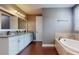 Bathroom featuring double sinks, white cabinets, granite counters and a soaking tub at 3615 S Church Ave, Tampa, FL 33629