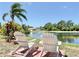 Relaxing backyard featuring two Adirondack chairs overlooking a serene lake and lush tropical landscaping at 408 Delwood Breck St, Ruskin, FL 33570