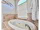 Elegant soaking tub features tile surround and abundant light from the arched window at 408 Delwood Breck St, Ruskin, FL 33570