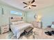 Bedroom features light, airy colors, wood-look floors, a ceiling fan, and a comfortable chair with footstool at 408 Delwood Breck St, Ruskin, FL 33570