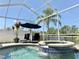 Relaxing screened-in pool and spa with a sun umbrella and palm trees at 408 Delwood Breck St, Ruskin, FL 33570