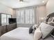 Comfortable bedroom with a queen-sized bed, TV, and natural light from windows with shutters at 4689 Wandering Way, Wesley Chapel, FL 33544