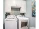 Functional laundry room featuring washer, dryer, cabinets, and subway tile backsplash at 4689 Wandering Way, Wesley Chapel, FL 33544