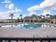 Beautiful community pool and lounge area with palm trees under a blue sky with fluffy white clouds at 4689 Wandering Way, Wesley Chapel, FL 33544