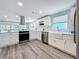 This renovated kitchen offers stainless appliances, white cabinetry, and durable wood-look flooring at 4920 Pelican Dr, New Port Richey, FL 34652